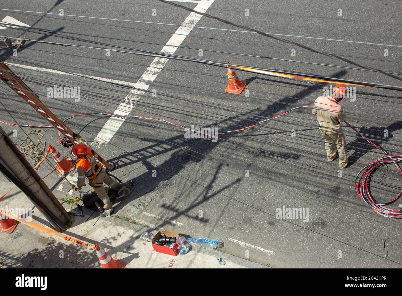 Uomini che riparano i fili elettrici della rete utilizzando maschere a causa di COVID-19 Foto Stock