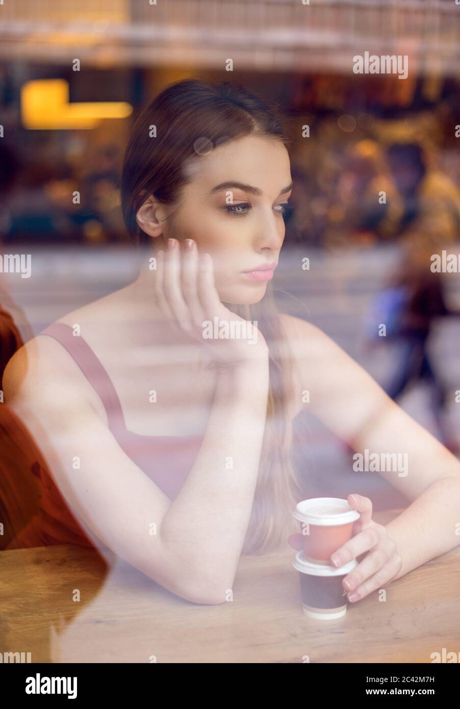 Ritratto di giovane donna al bar guardando fuori dalla finestra Foto Stock