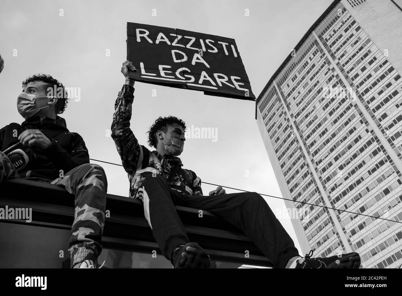 Il protetore tiene un cartello con la scritta 'Razzisti da Legare'urando l'assemblea di protesta in solidarietà con il movimento BLM.Pirelli torre sullo sfondo Foto Stock