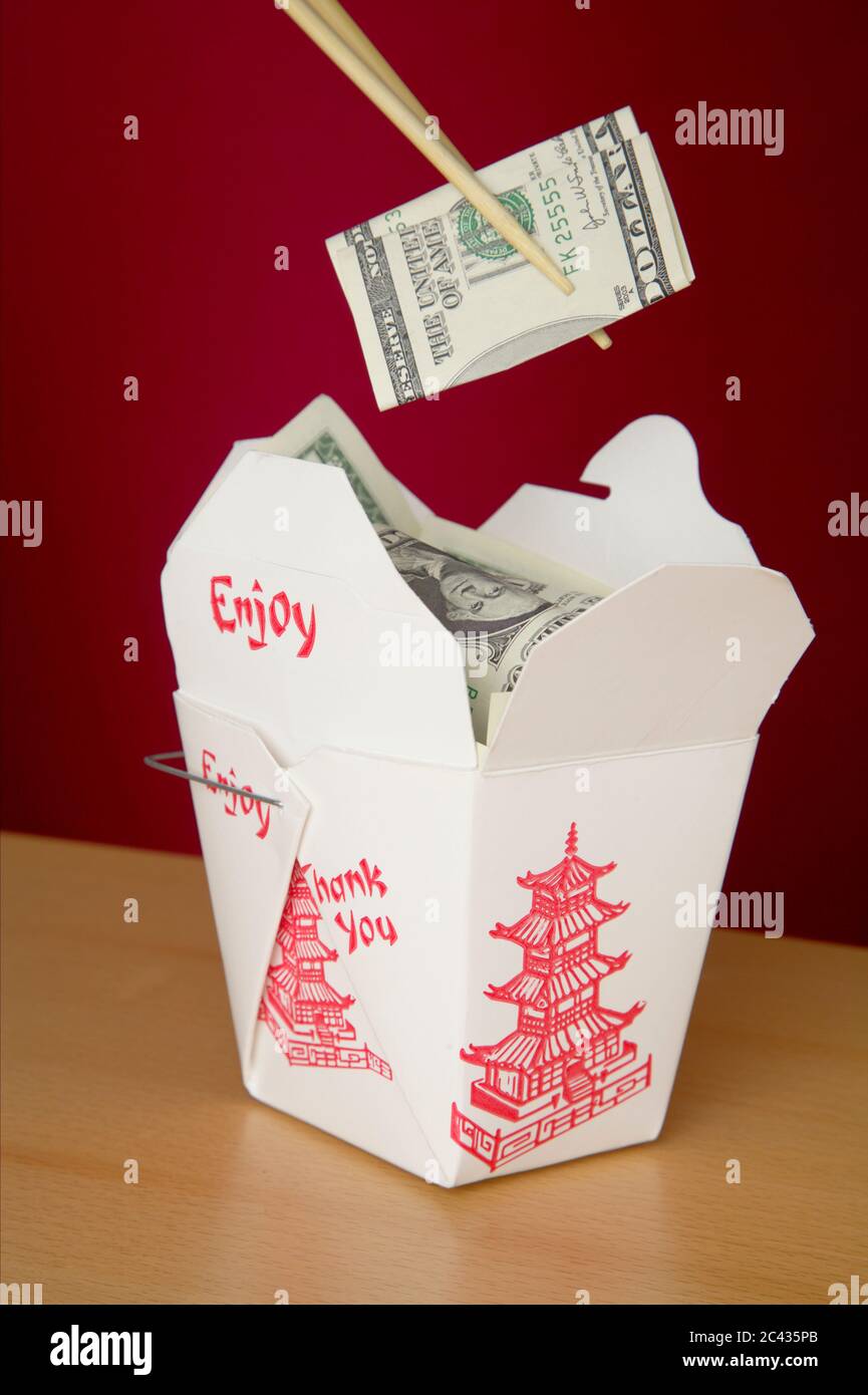 Bollette in dollari tra i bastoncini e in una scatola per il cibo asiatico Foto Stock