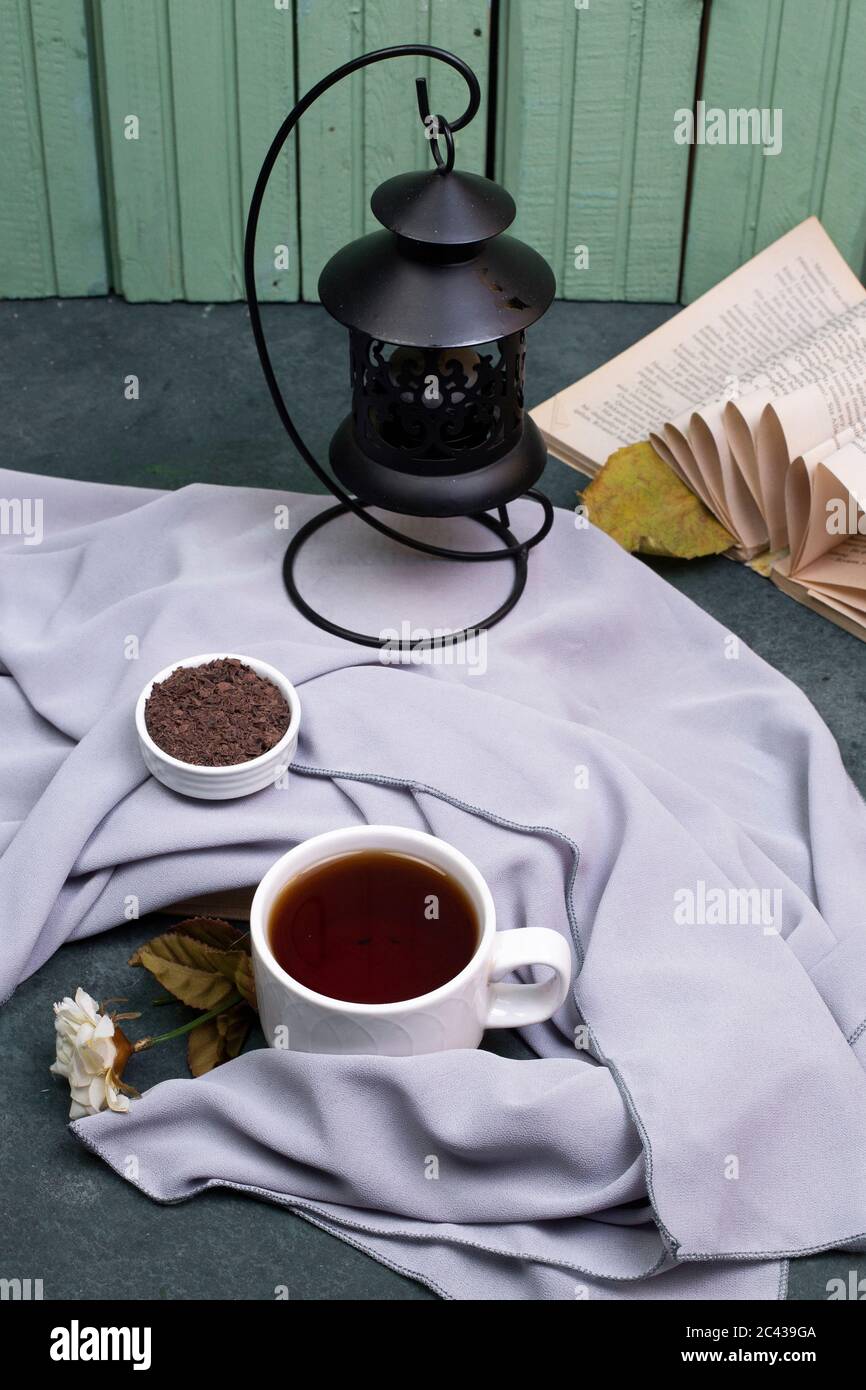 Una tazza di tè e di erbe in un piatto sul tavolo, un libro intorno Foto Stock