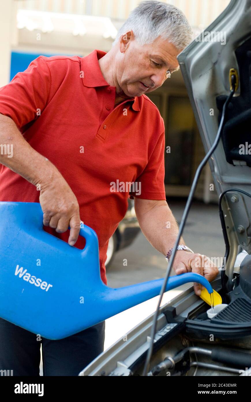 L'uomo maturo riforniva d'acqua nella sua auto, Monaco, Baviera, Germania Foto Stock