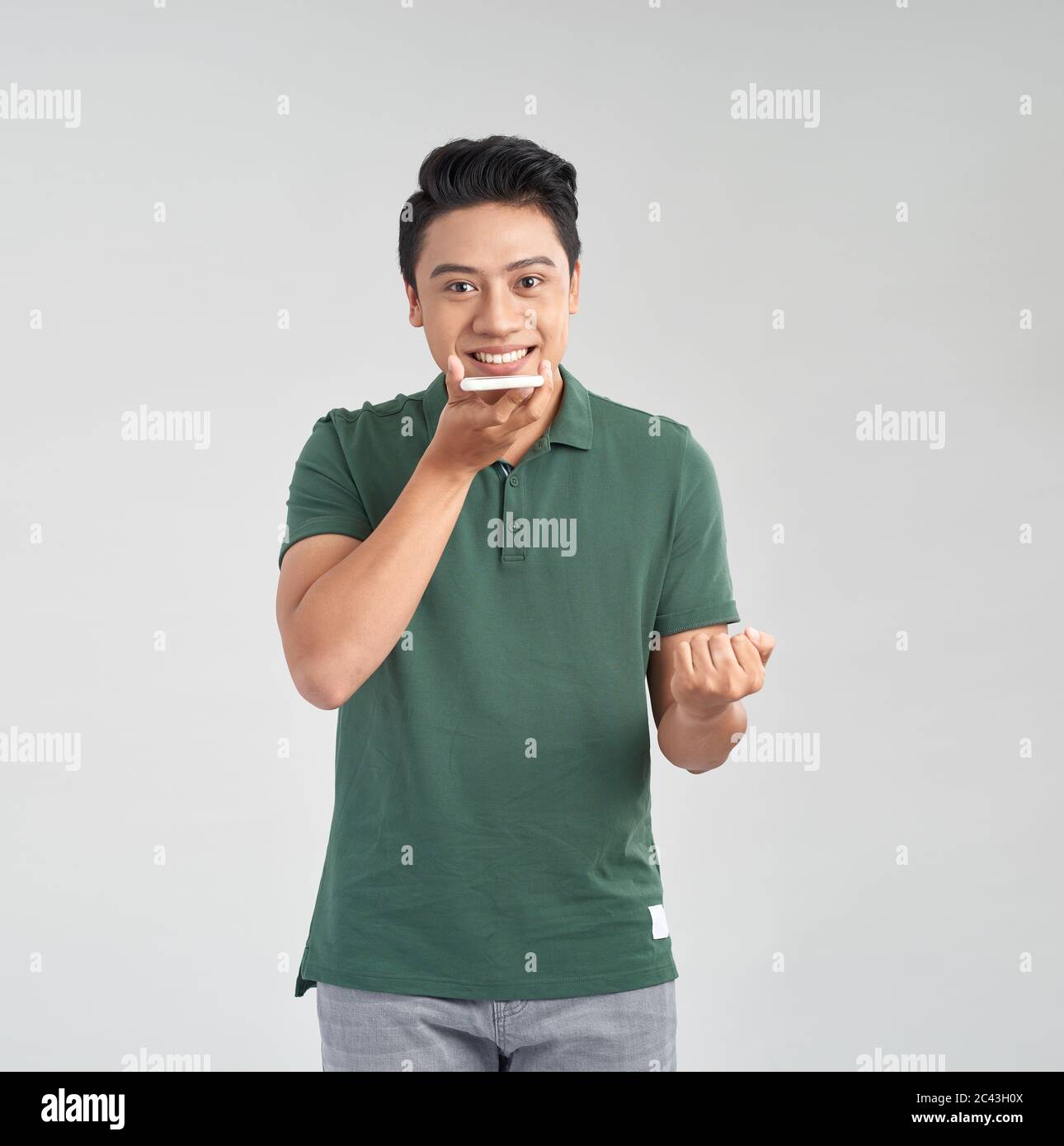 Giovane asiatico che utilizza una funzione di riconoscimento vocale dello smartphone isolata su sfondo bianco Foto Stock