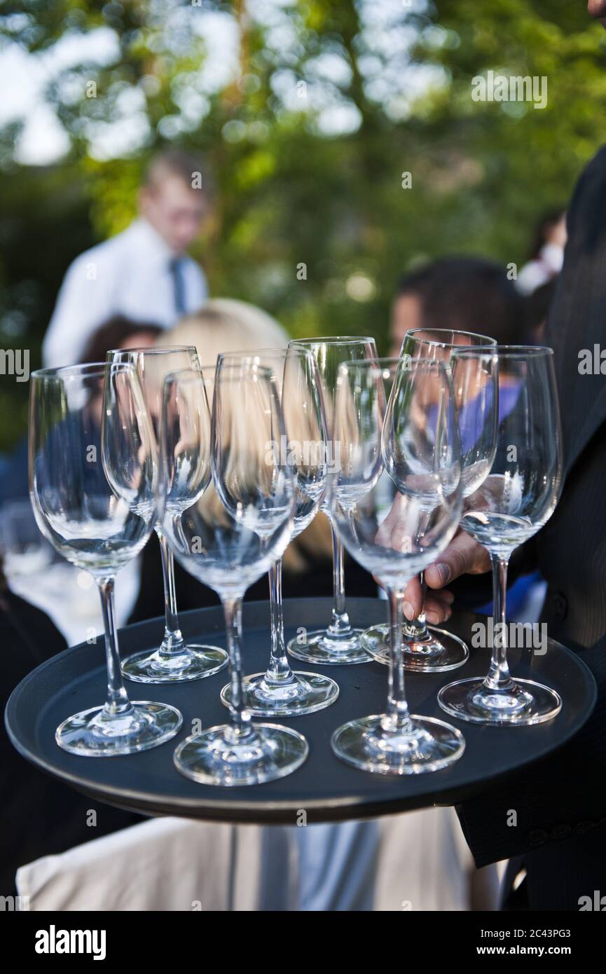 Uomo che tiene un vassoio di bicchieri da vino in un ristorante all'aperto Foto Stock