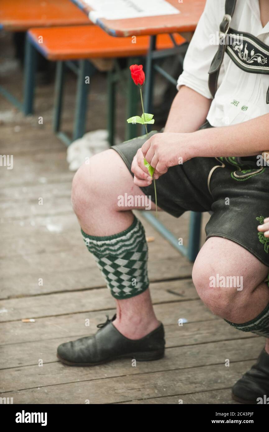 L'uomo in abiti tradizionali bavaresi tiene una rosa Foto Stock