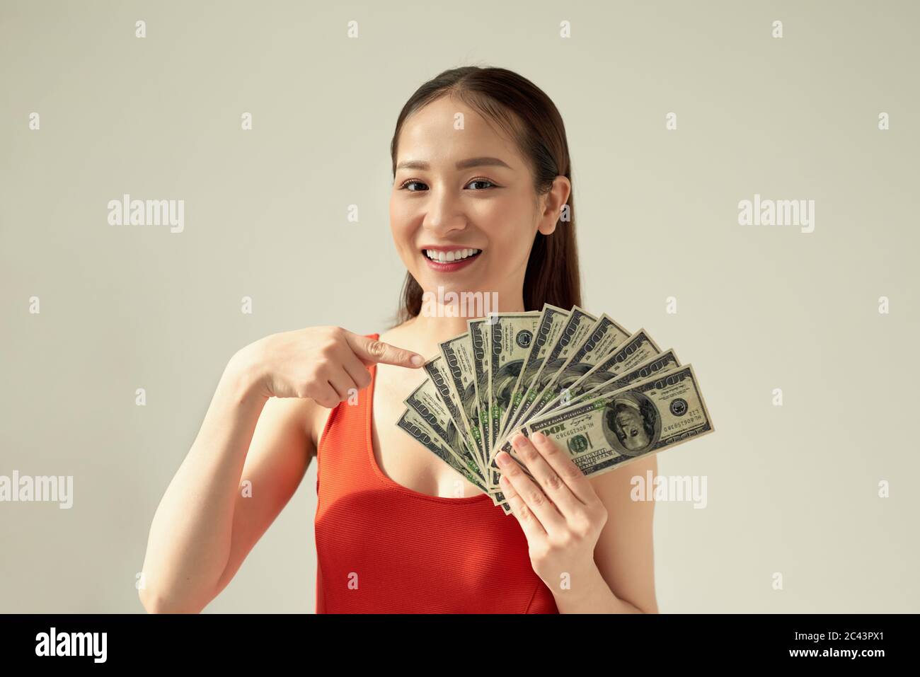 Ritratto di successo donna 20s che tiene lotti di banconote in dollari isolato su sfondo luminoso Foto Stock