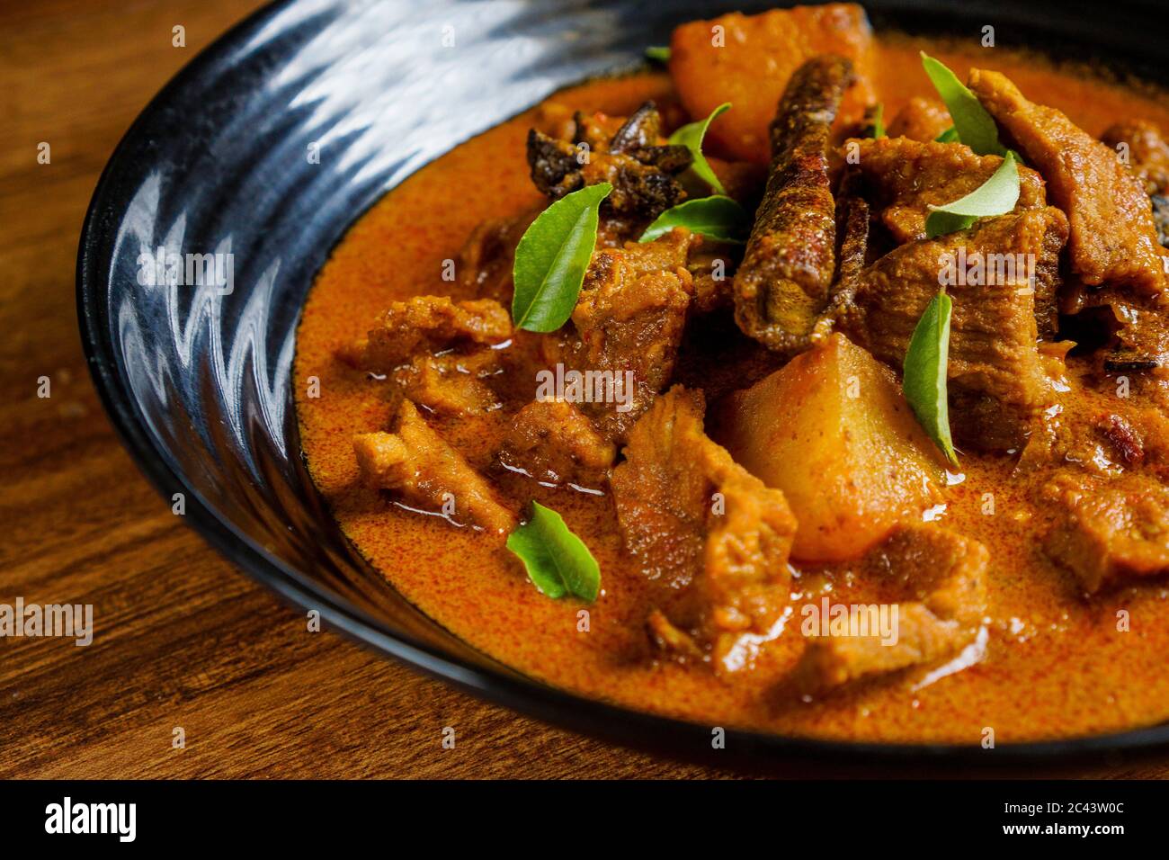 Carne di agnello cotta al curry con patate e spezie e guarnita con foglie di curry. Foto Stock