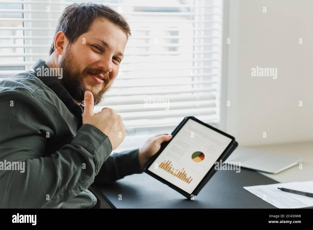 Broker di successo che mostra i thums e l'utilizzo di tablet con grafici. Foto Stock