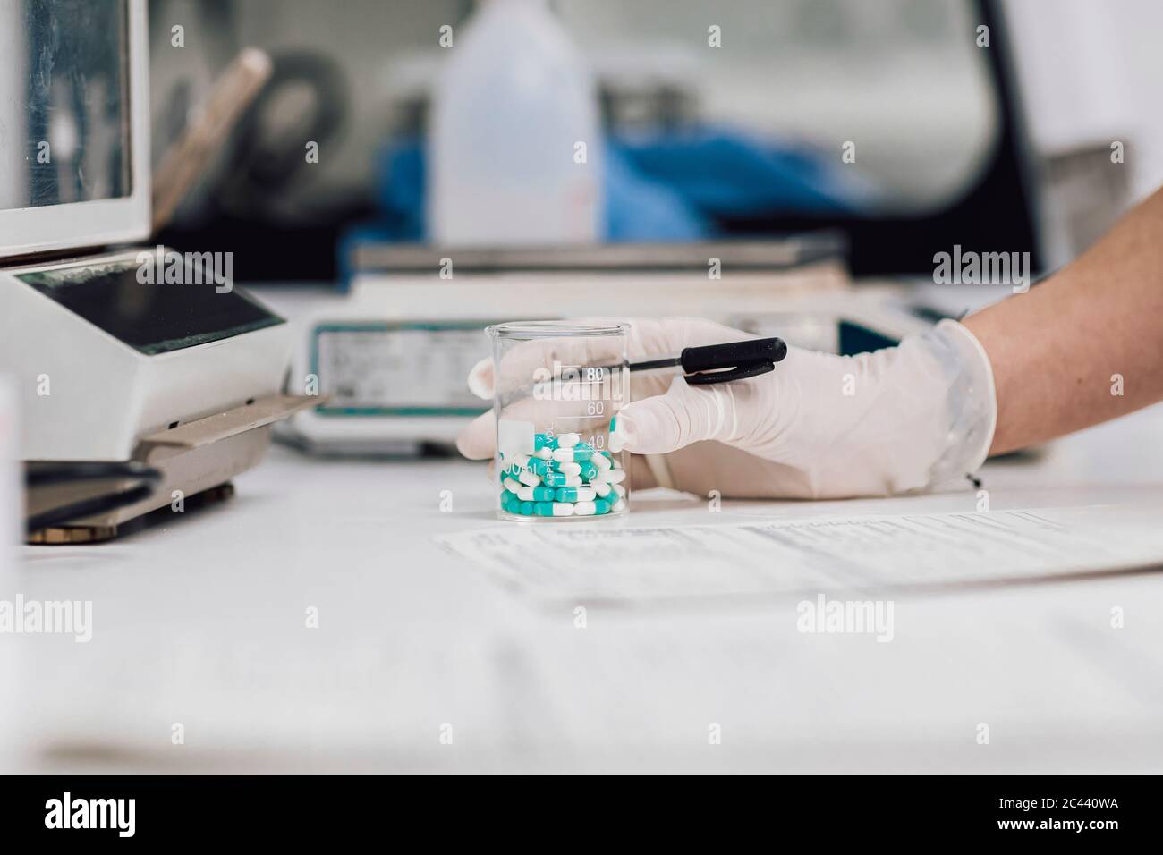 Primo piano di una becher femminile con compresse sulla scrivania del laboratorio Foto Stock