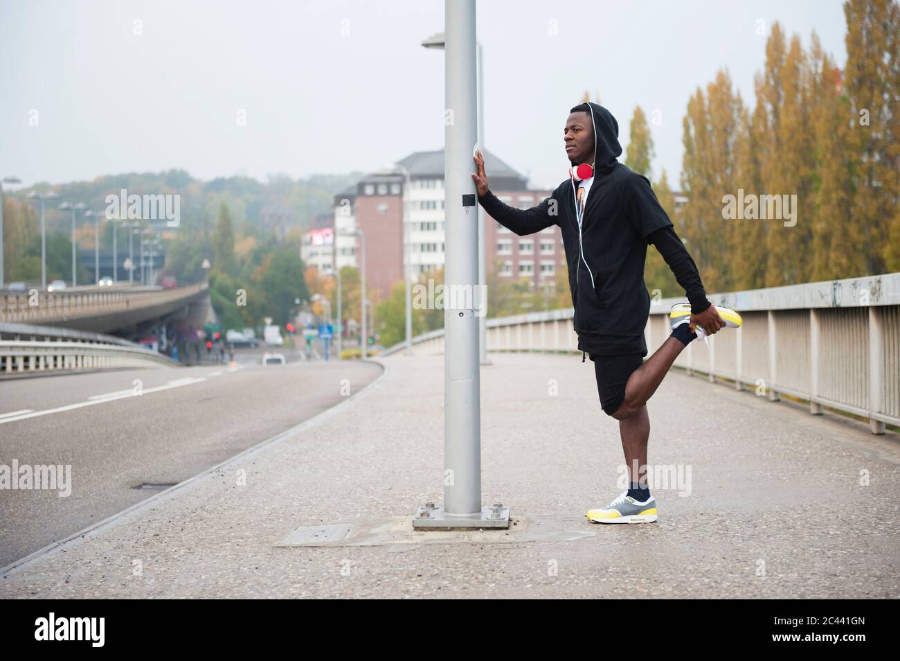 Giovane jogger che allunga la gamba in città Foto Stock
