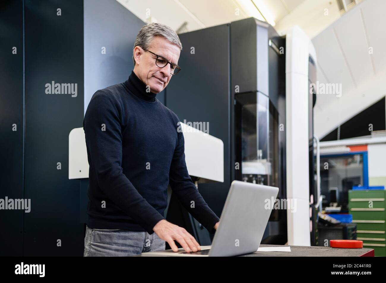 Supervisore maschile maturo che utilizza il computer portatile in fabbrica Foto Stock