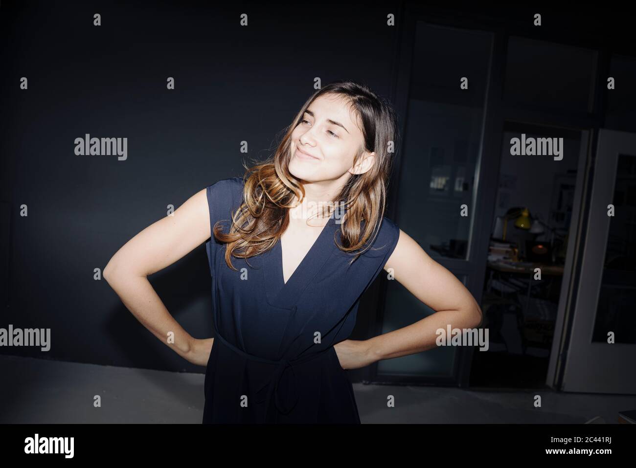 Ritratto di sorridente giovane donna con le mani sui fianchi Foto Stock