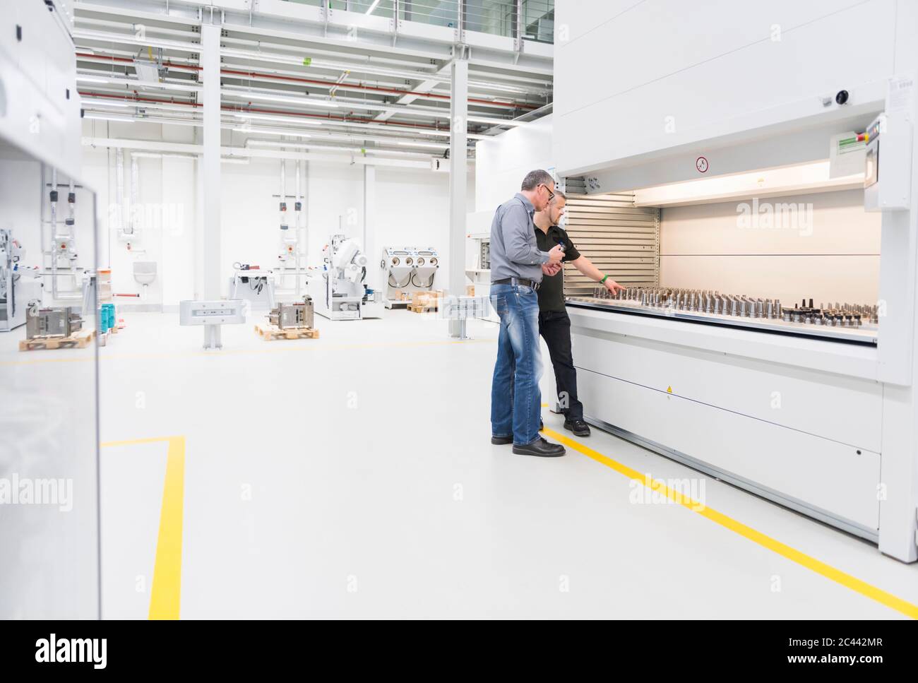 Due uomini che parlano ad una macchina in una fabbrica Foto Stock