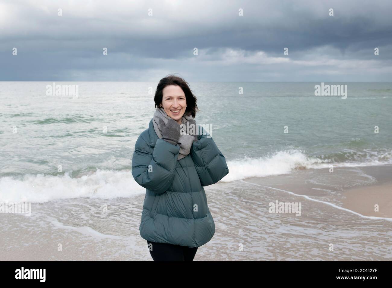 Russia, Kaliningrad Oblast, Zelenogradsk, Ritratto di giovane donna in piedi sulla spiaggia costiera e sorridente alla macchina fotografica Foto Stock