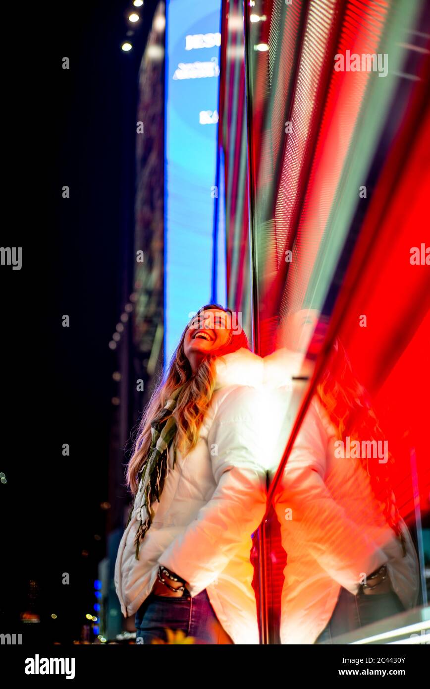 Stati Uniti d'America, New York New York City, Ritratto di giovane donna bella poggiando su Times Square il display a LED di notte Foto Stock