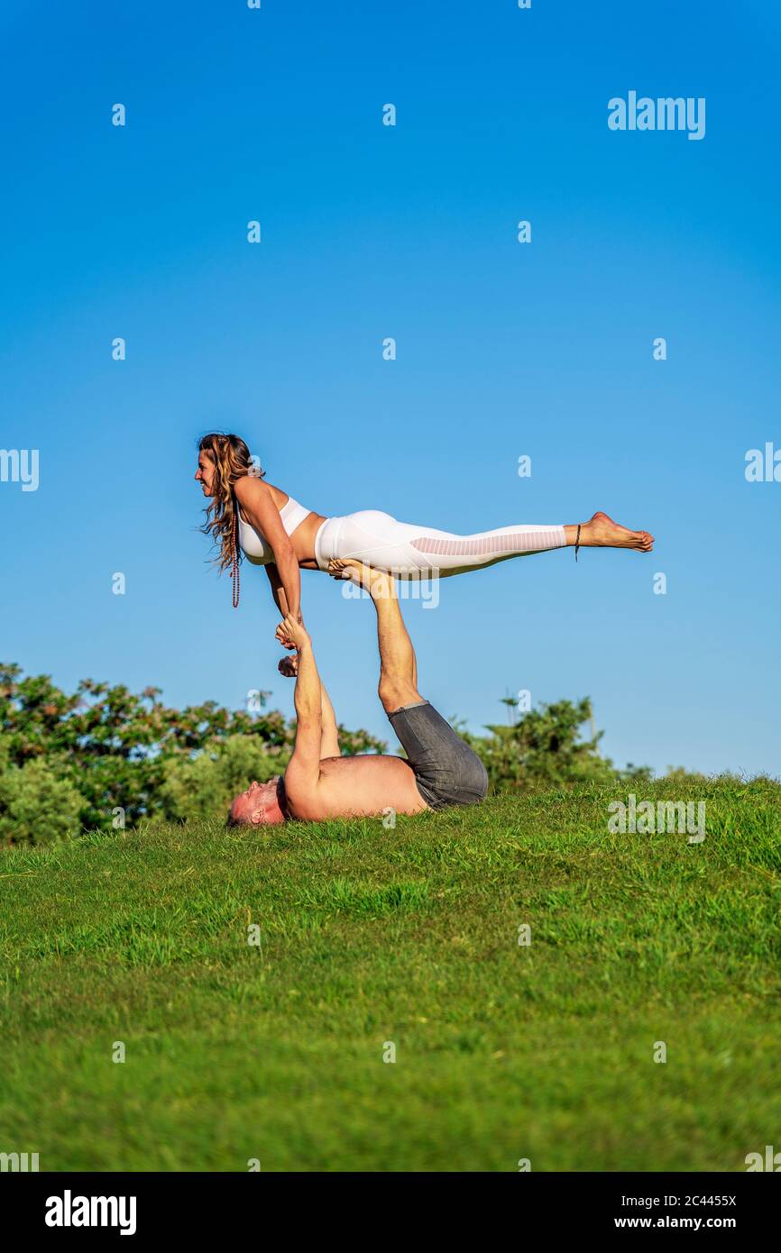 Coppia matura che fa yoga sul prato al sole insieme Foto Stock