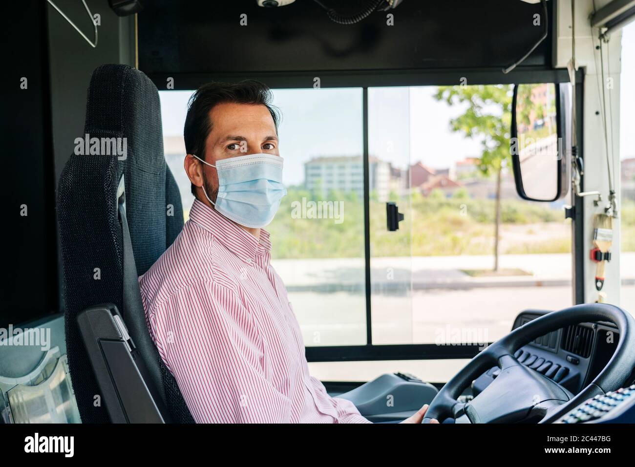 Ritratto di conducente di autobus maturo indossare maschera protettiva, Spagna Foto Stock