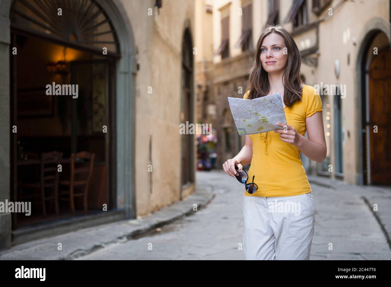 Ritratto di donna con mappa della città in piedi in un vicolo che guarda a distanza, Firenze, Italia Foto Stock