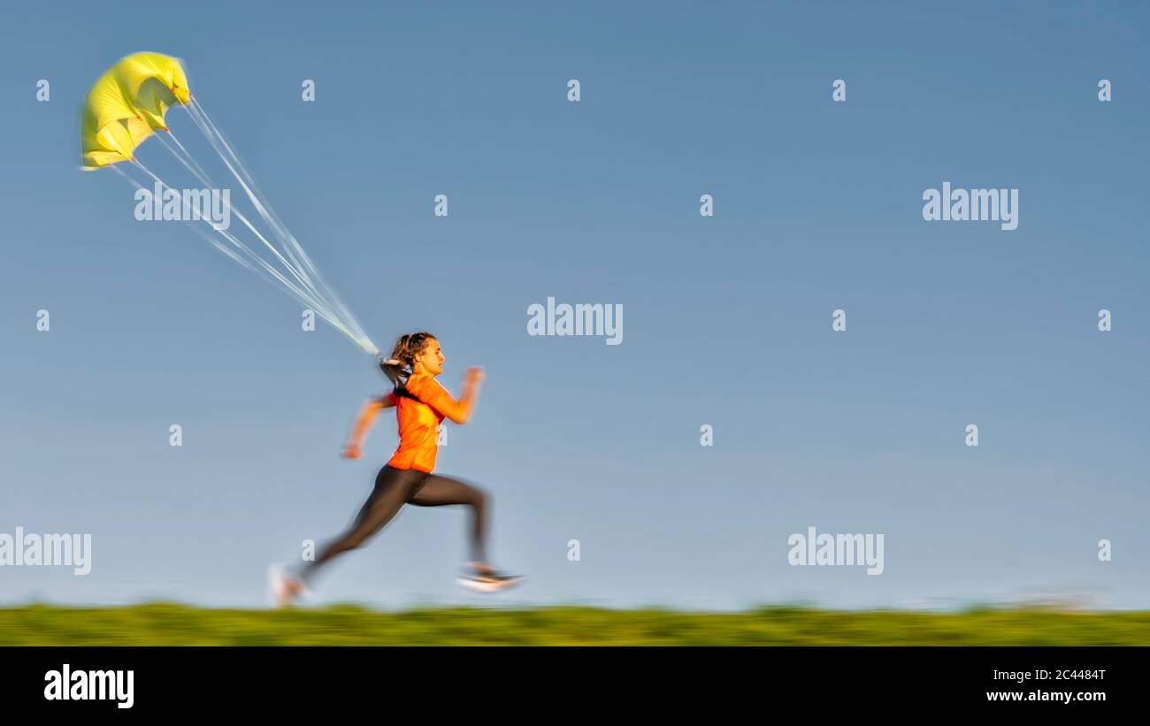 Vista laterale della corsa con paracadute contro cielo blu chiaro Foto Stock