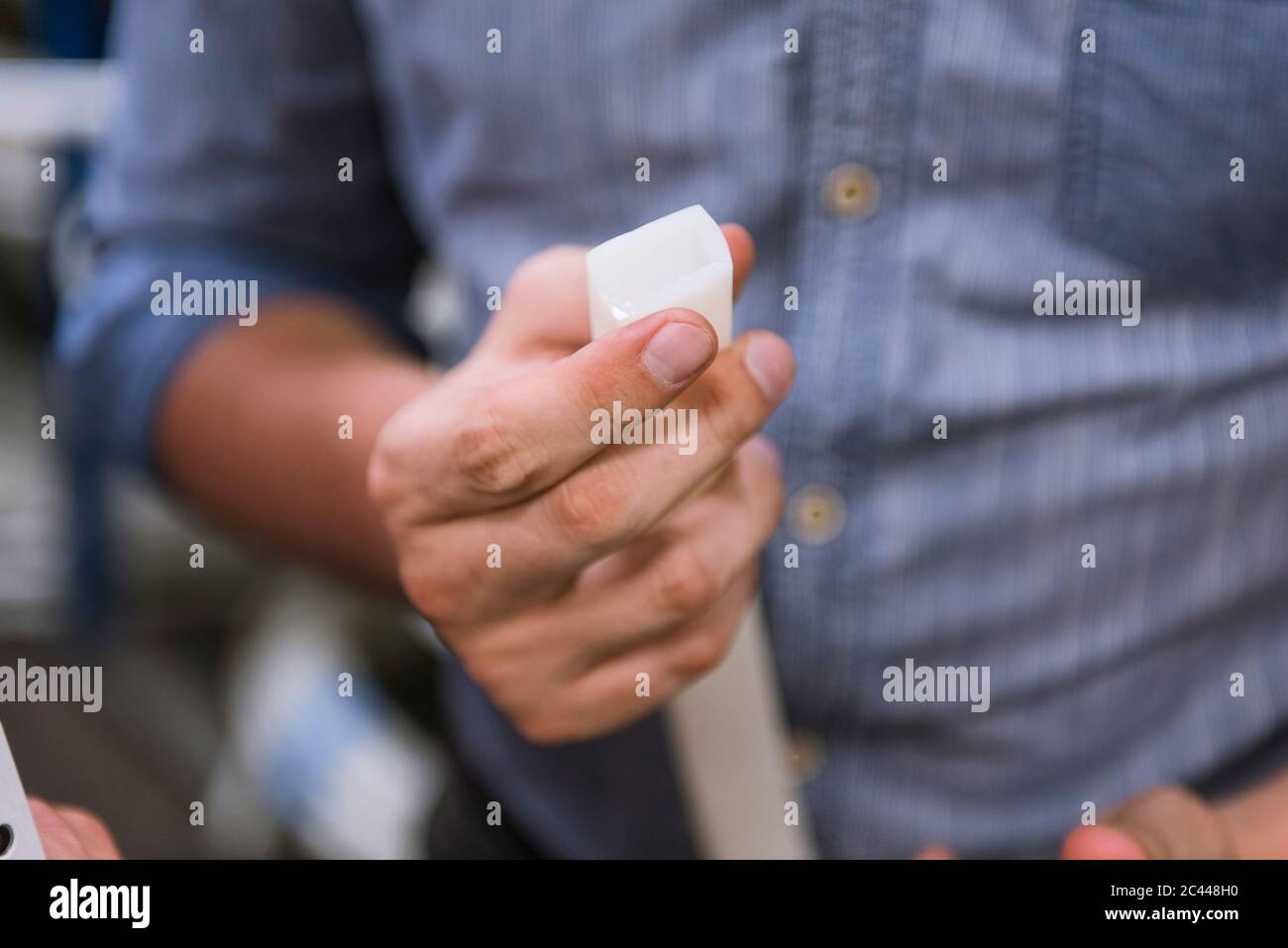 Primo piano di un uomo che detiene un prodotto in una fabbrica Foto Stock
