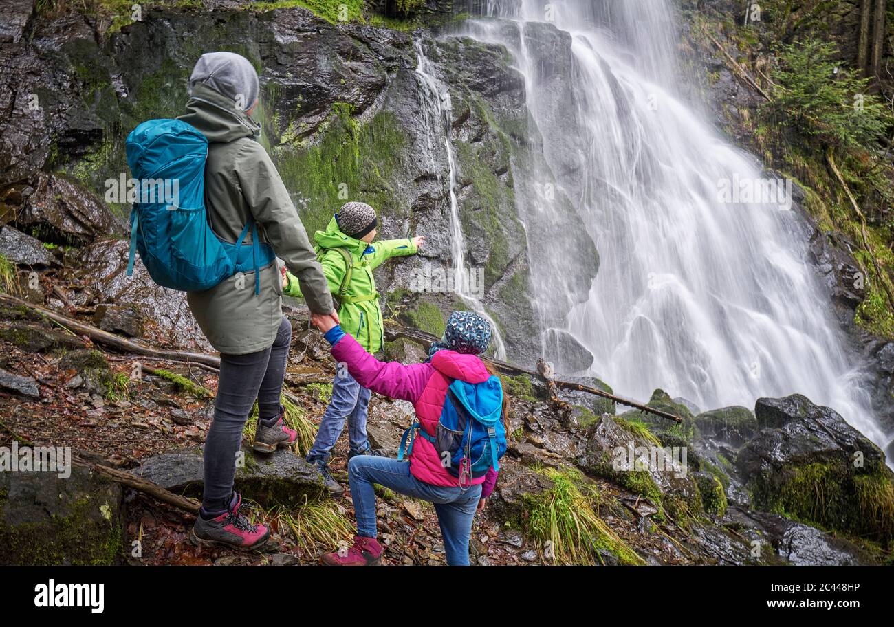 Madre con bambini in piedi vicino alla cascata Zweribach nella Foresta Nera settentrionale Foto Stock