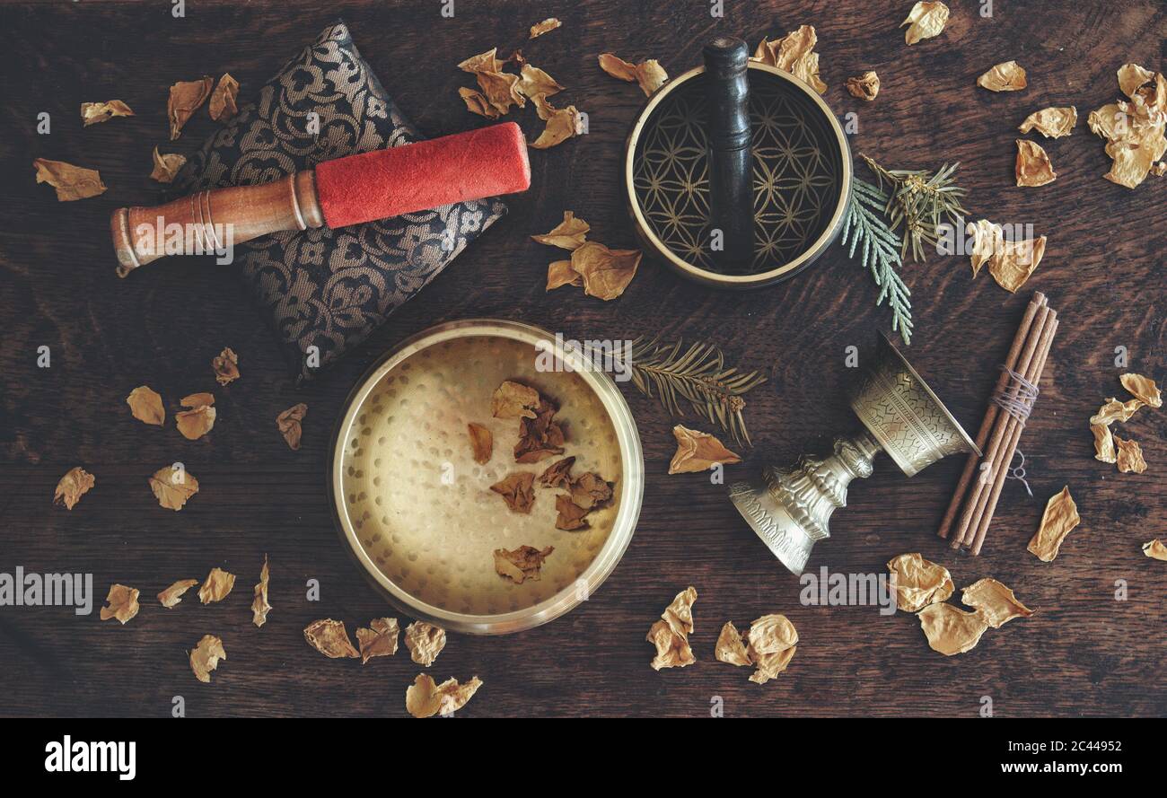 Piatto a tema tibetano con esempi di due diverse bocce cantanti - un marrone scuro, e uno di colore oro, e un antico portaincenso Foto Stock