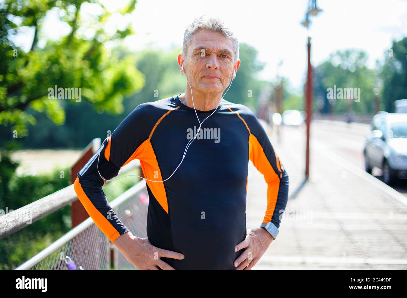 Ritratto di uomo anziano sicuro in abiti sportivi in piedi con le mani sull'anca durante la giornata di sole Foto Stock