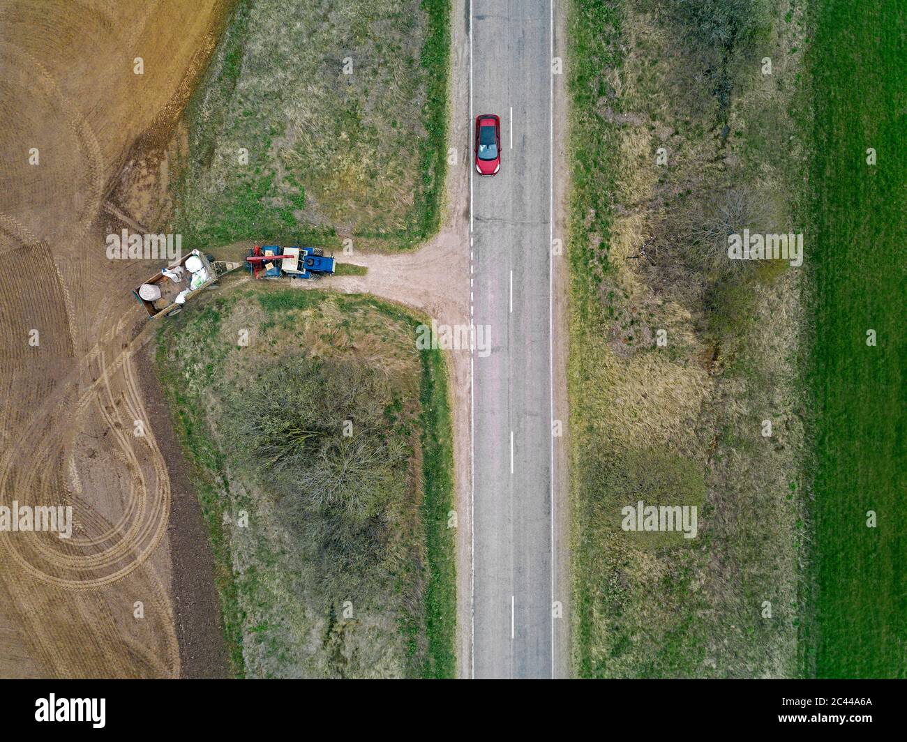 Russia, vista aerea della guida di auto lungo la strada di campagna che passa trattore arando campo adiacente Foto Stock