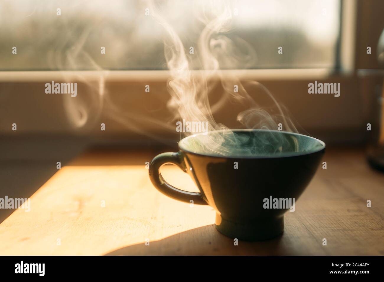 Vapore che si alza dal caffè appena preparato in tazza sul tavolo a casa Foto Stock