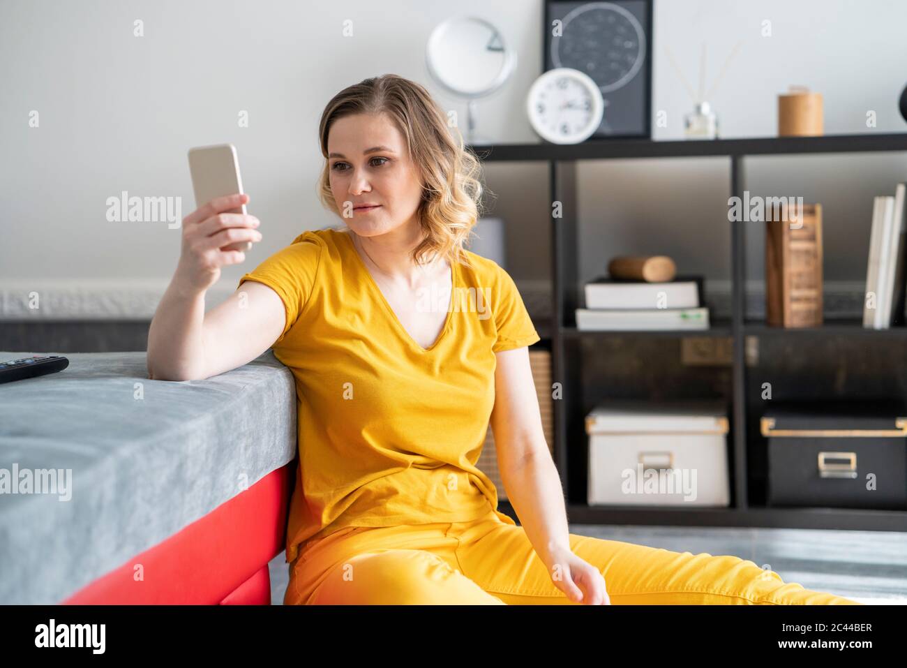 Donna che usa lo smartphone nel salotto di casa Foto Stock
