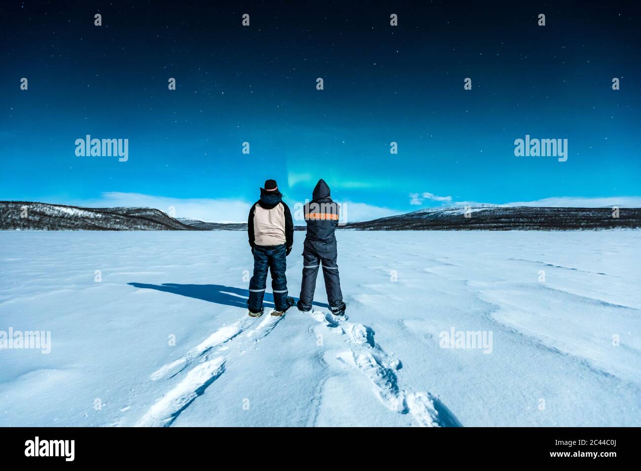 Gli escursionisti con racchette da neve che si trovano nel paesaggio invernale guardando l'aurora settentrionale sopra Ropijarvi, Ropinsalmi, Enontekioe, Finlandia Foto Stock