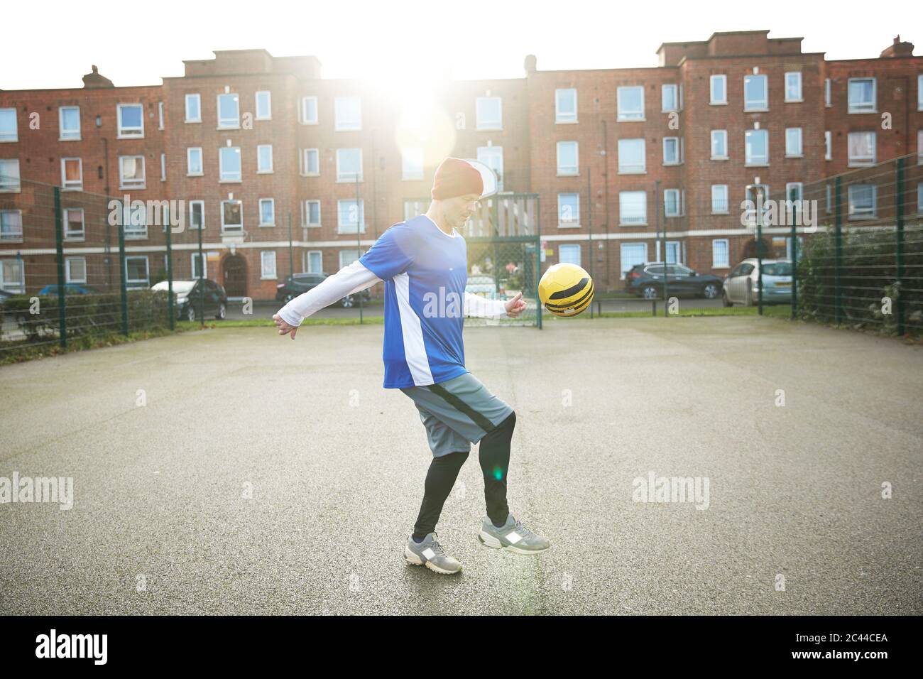 Uomo maturo che gioca con il calcio sul campo di calcio in città Foto Stock