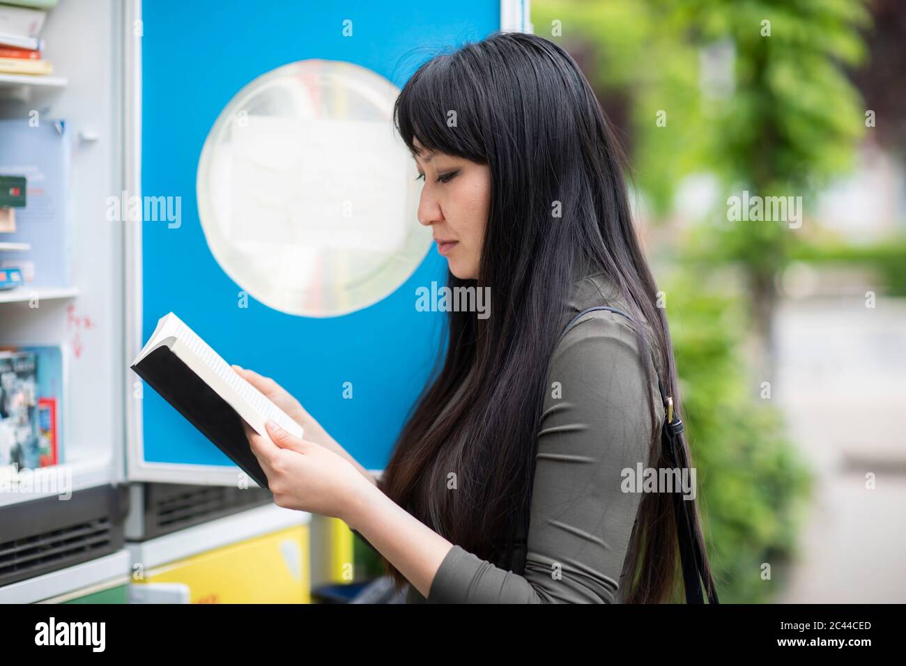 Donna che legge un libro al caso pubblico del libro Foto Stock