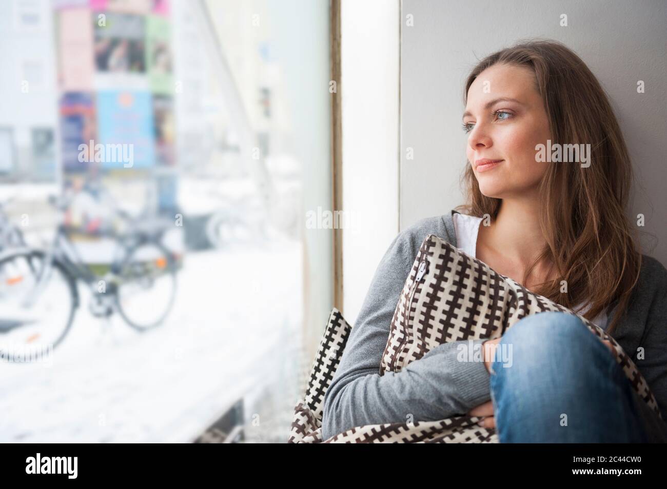 Ritratto di donna sognante in un bar che guarda attraverso la finestra in inverno Foto Stock