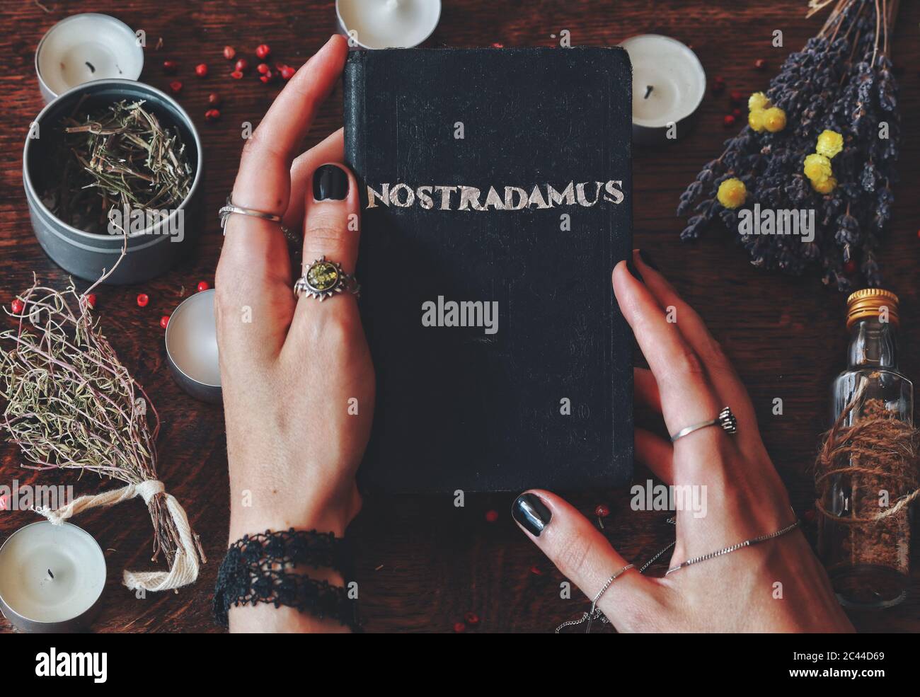 Wiccan strega tenendo a mano libro fatto con la parola di lamina d'argento Nostradamus scritto su di esso, circa predire il futuro e profezie antiche nelle sue mani Foto Stock