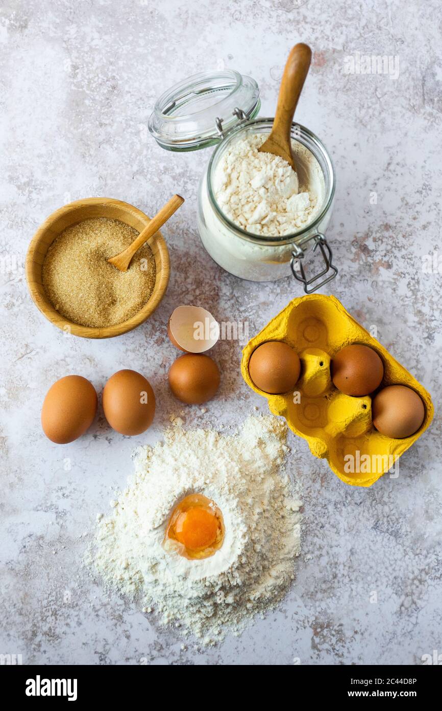 Tuorlo d'uovo in farina, uova di pollo, recipiente di zucchero di canna e vaso di farina Foto Stock