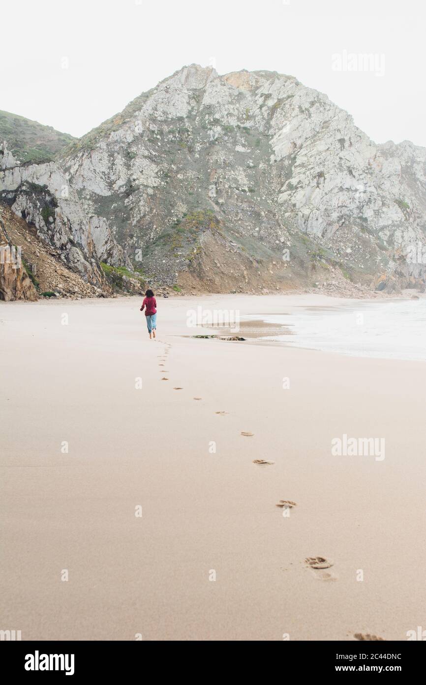 Donna che lascia le impronte mentre corre a Ursa Beach, Lisboa Regione, Portogallo Foto Stock