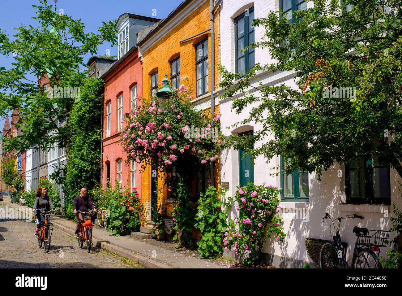 Danimarca, Copenaghen, uomo e donna in bicicletta lungo la strada del quartiere storico di Nyboder Foto Stock