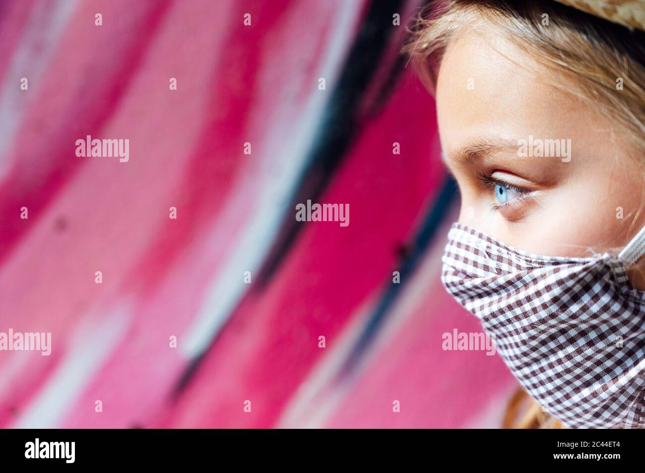 Primo piano di ragazza con occhi blu che indossa maschera facciale mentre si guarda via Foto Stock