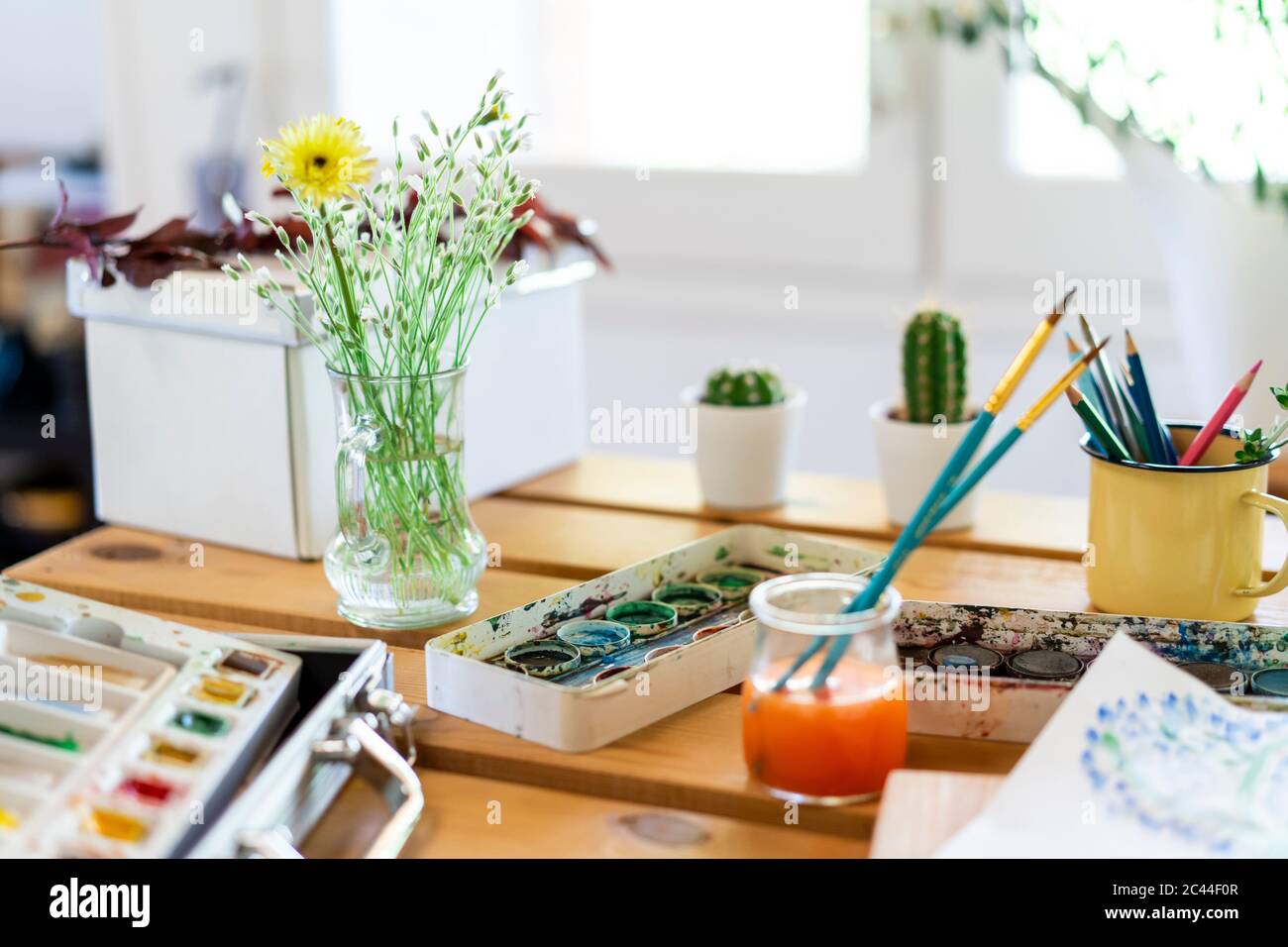 Vernici acquerello con vaso di fiori e pennelli su tavola di legno casa Foto Stock