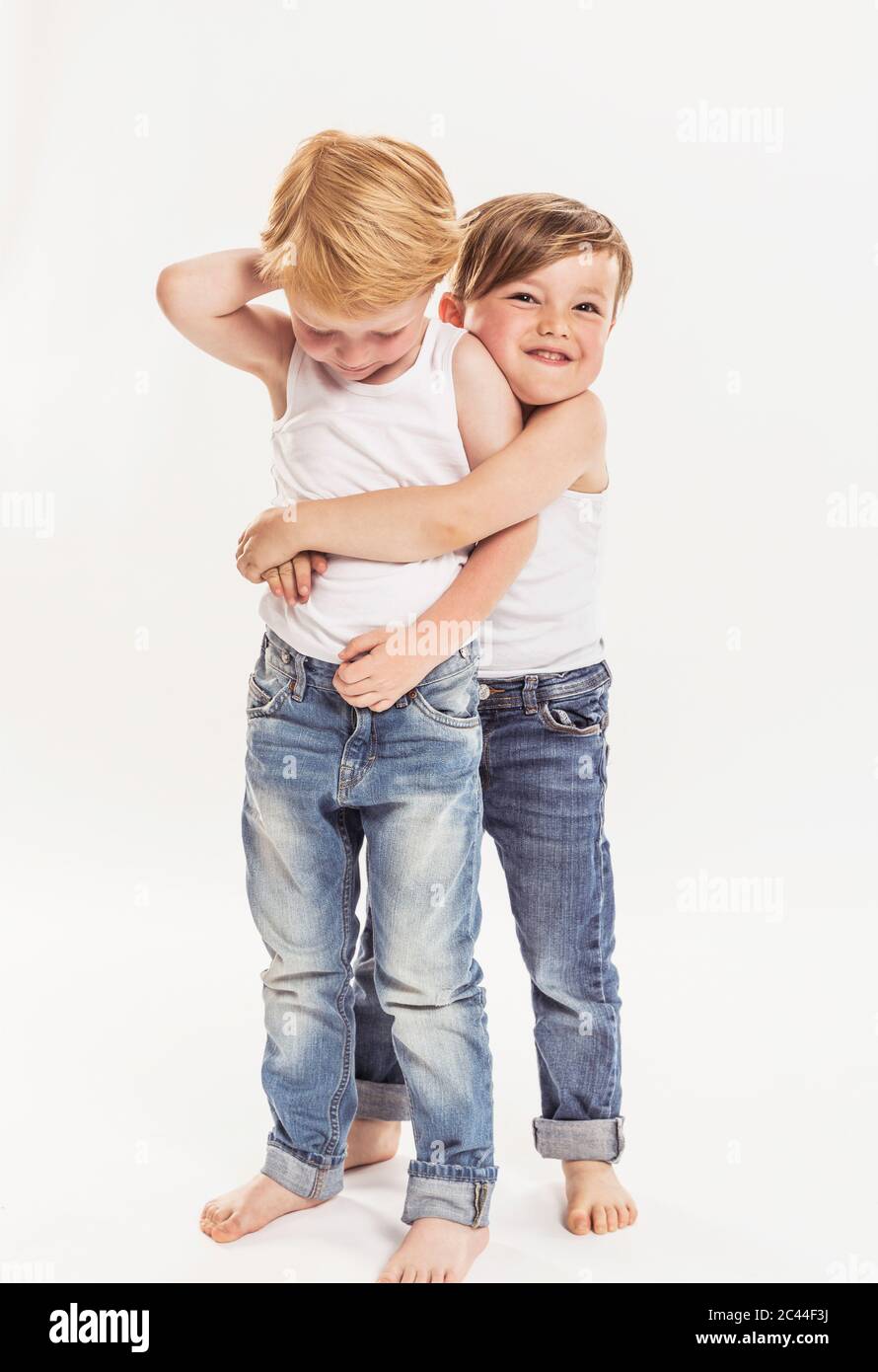 Ritratto di ragazzino che abbracciava l'altro ragazzino davanti a sfondo bianco Foto Stock