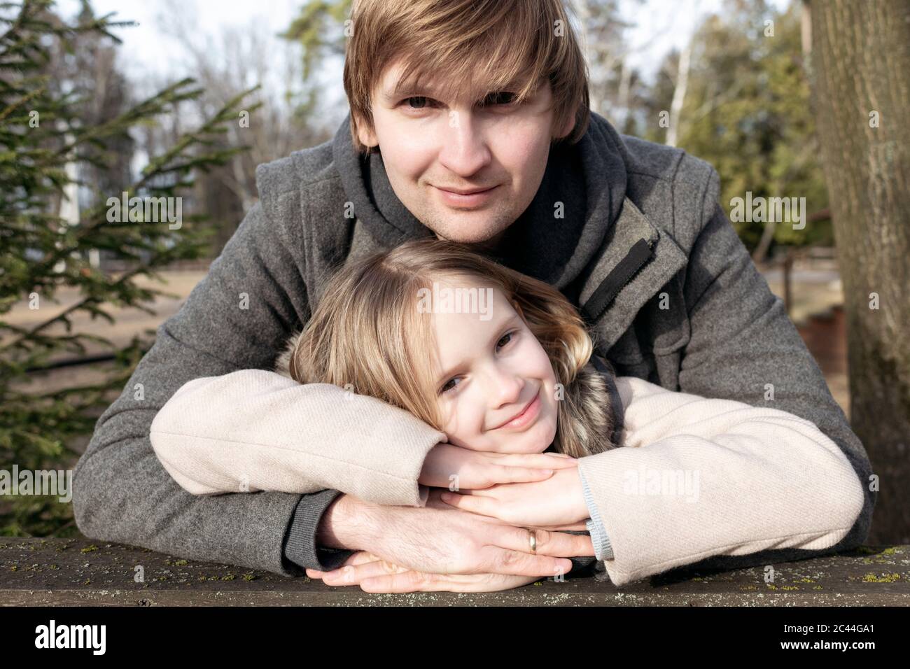 Ritratto di sorridente ragazza appoggiata sulle mani del padre in cortile durante il giorno di sole, Tarusa, Russia Foto Stock
