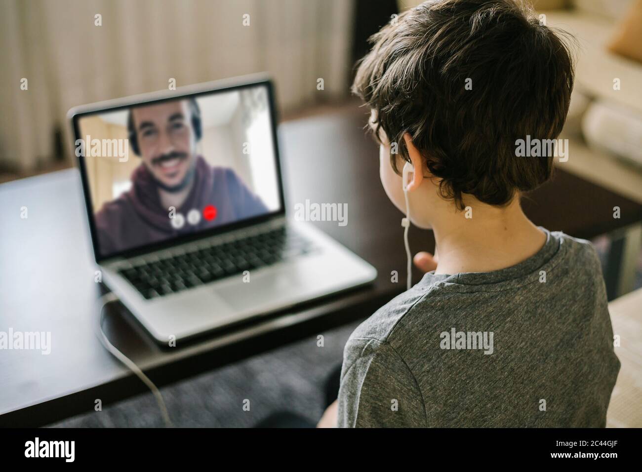 Ragazzo che usa un laptop per la chat video con suo padre Foto Stock