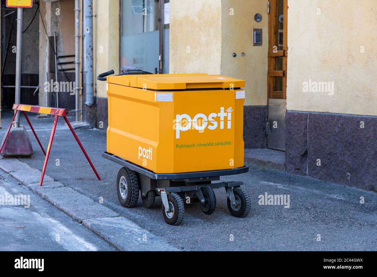 Moderno carrello elettrico per posta di Posti finlandese di fronte a un edificio residenziale a Helsinki, Finlandia Foto Stock
