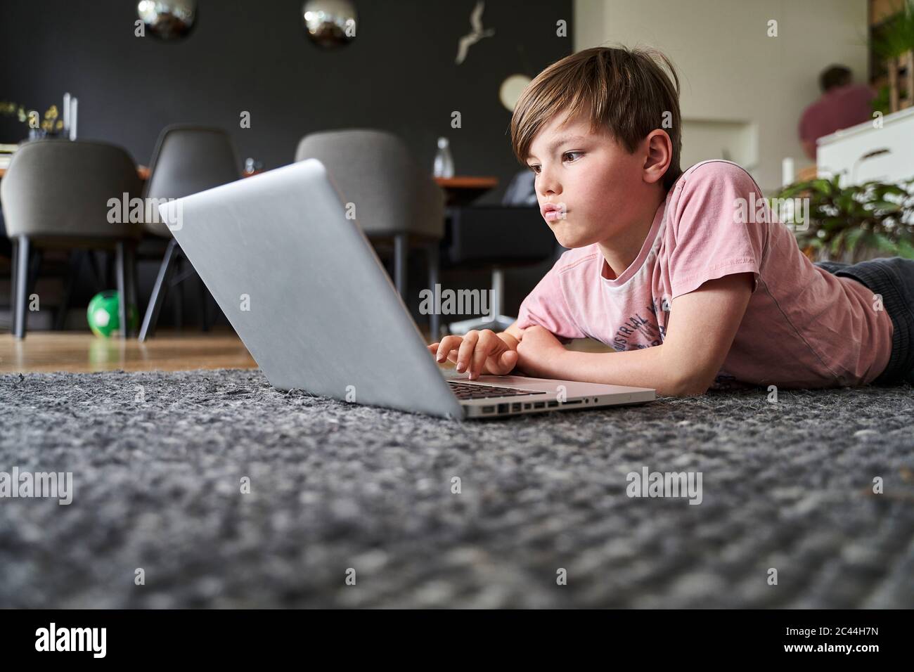 Ragazzo che si trova sul pavimento, che lavora su un computer portatile Foto Stock