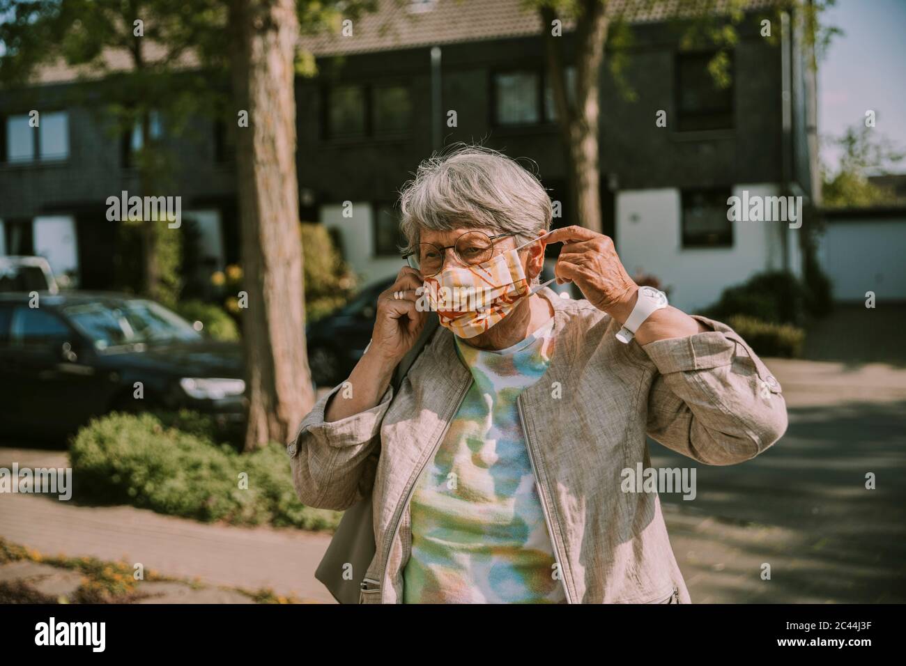 Donna ritirata che indossa una maschera protettiva mentre si trova all'aperto in una giornata di sole Foto Stock