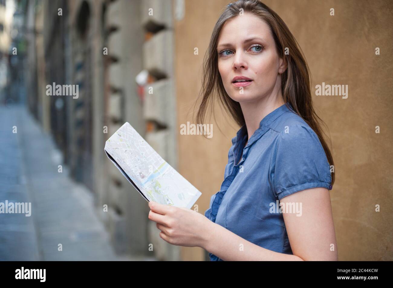 Ritratto di donna con mappa della città in piedi in un vicolo che guarda a distanza, Firenze, Italia Foto Stock