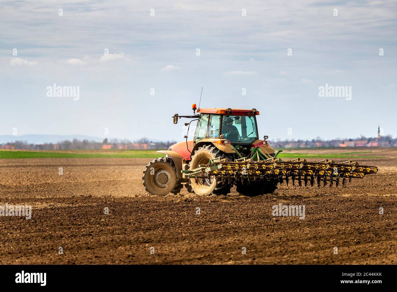 Coltivatore in campo di aratura trattore in primavera Foto Stock