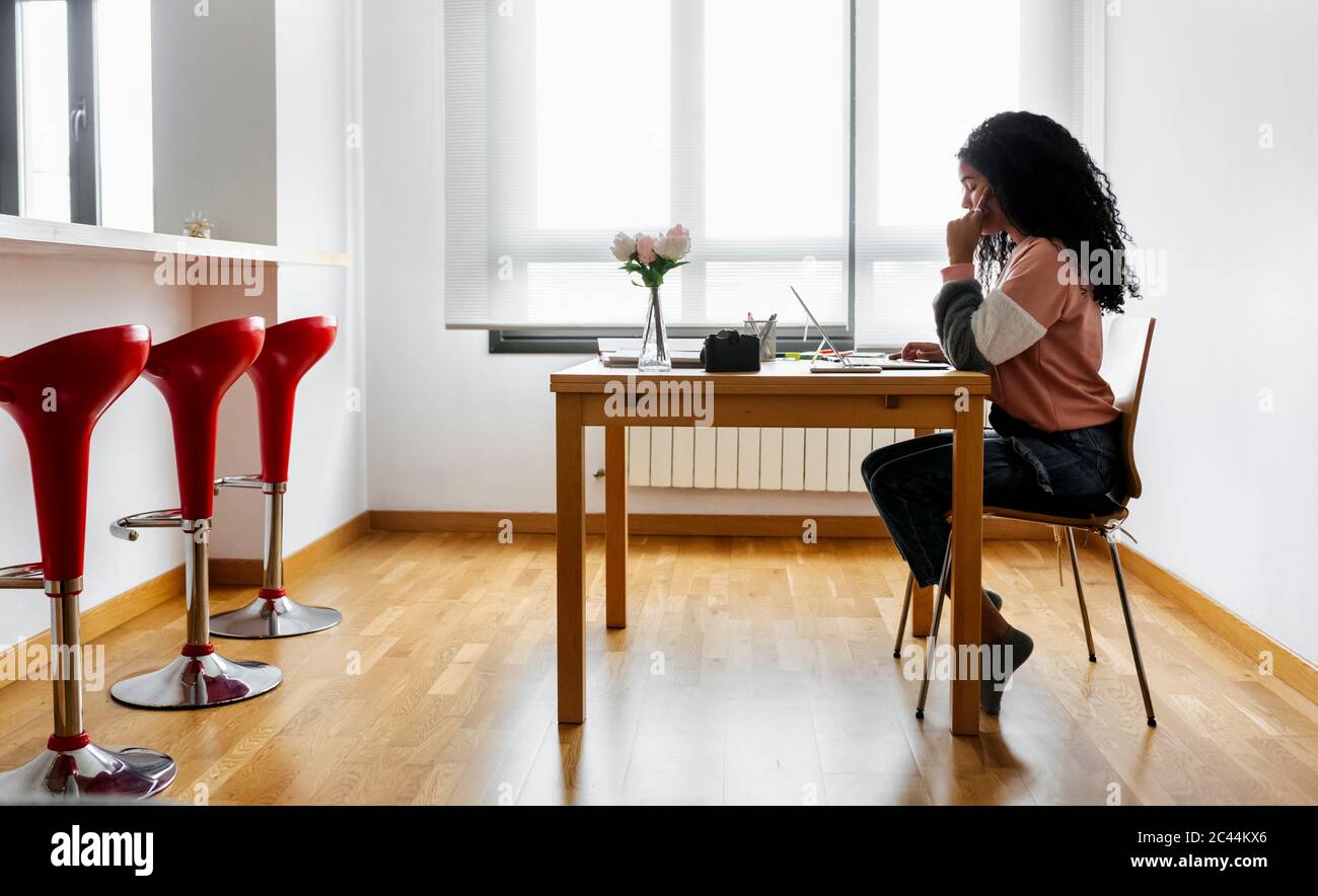 Giovane donna che lavora da casa utilizzando un computer portatile Foto Stock