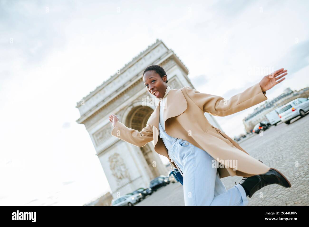 Giovane donna allegra contro l'Arco di Trionfo durante il giorno di sole, Parigi, Francia Foto Stock